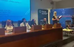 Kobiety i mężczyźni siedzą w sali konferencyjnej. Zebrani to kobiety i mężczyźni, którzy siedzą za stołem prezydialnym na podwyższeniu. Dwie osoby ubrane są w policyjne mundury. W tle telebim z napisem: „Panel dyskusyjny dokąd zmierzamy”. W dole zdjęcia s